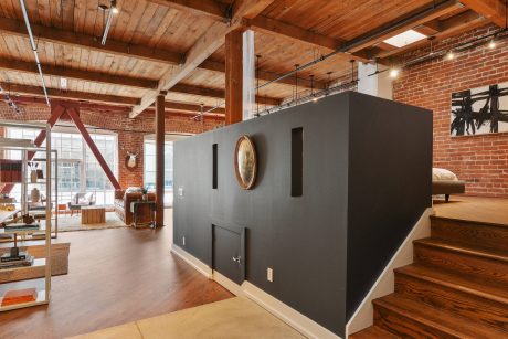 Rustic warehouse conversion with exposed brick, wooden beams, and a monochromatic accent wall.