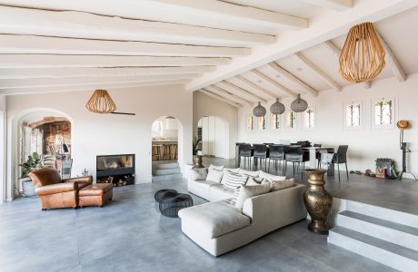 Spacious open-plan living area with exposed ceiling beams, pendant lighting, and sleek furnishings.