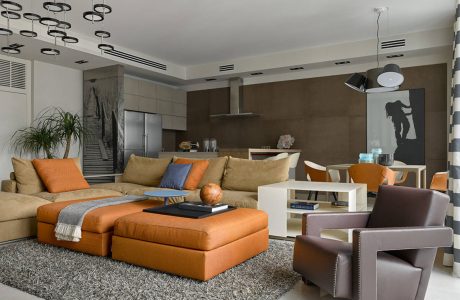 Modern living room with plush orange sectional, artwork, and pendant lighting.