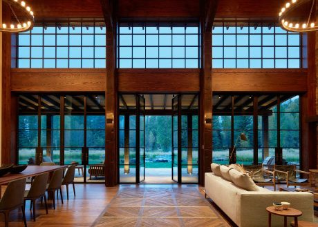 Spacious wooden lodge interior with large windows overlooking lush outdoor scenery.