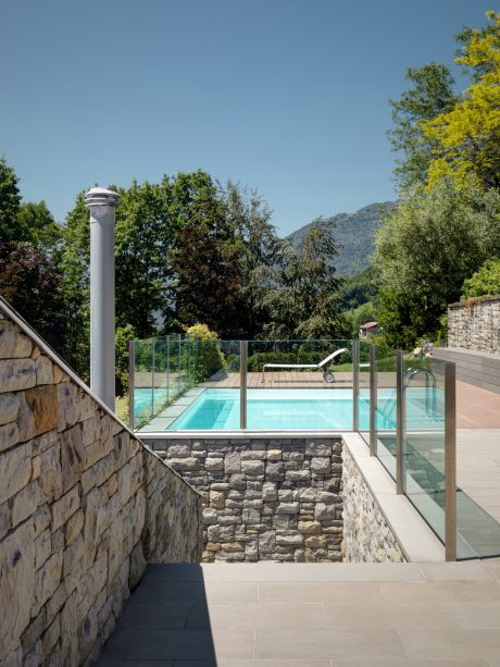 Stunning stone wall-enclosed pool surrounded by lush greenery and mountainous backdrop.