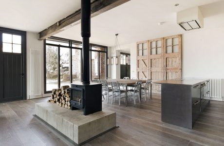 Modern, open-concept living space with concrete fireplace, wooden accents, and industrial lighting.