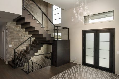 Sleek, modern staircase with steel railing, pendant lighting, and geometric tile flooring.