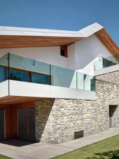 A contemporary home with glass walls, a wooden roof, and a stone facade blending seamlessly.