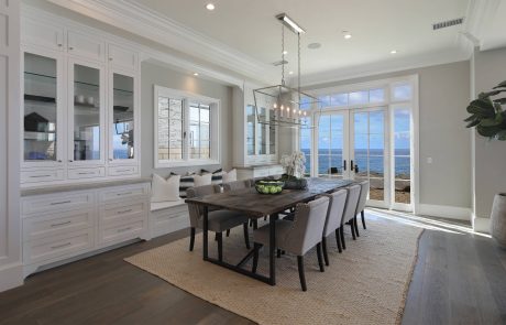 Spacious, bright dining room with expansive windows, sleek cabinetry, and modern chandelier.