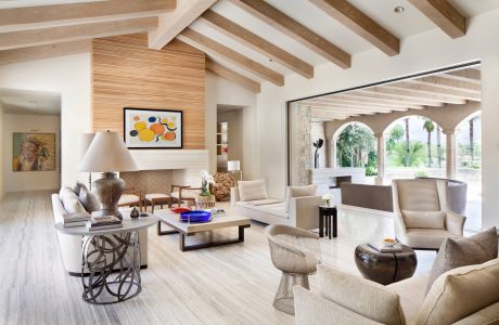 Bright, open-concept living space with wood-beamed ceiling, stone arches, and modern furnishings.