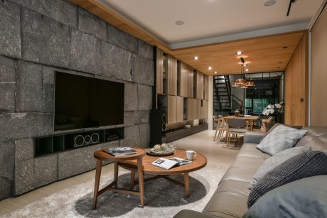 Sleek modern interior design with stone walls, wood paneling, and minimalist furniture.