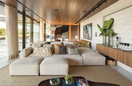 A spacious, open-concept living room with a wooden ceiling, plush sofas, and modern furnishings.