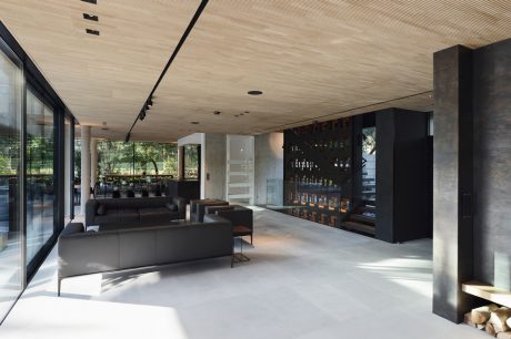 Spacious modern interior with sleek furniture, wood-paneled ceiling, and built-in bar.