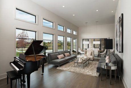 Spacious, open-concept living room with grand piano, large windows, and modern furnishings.