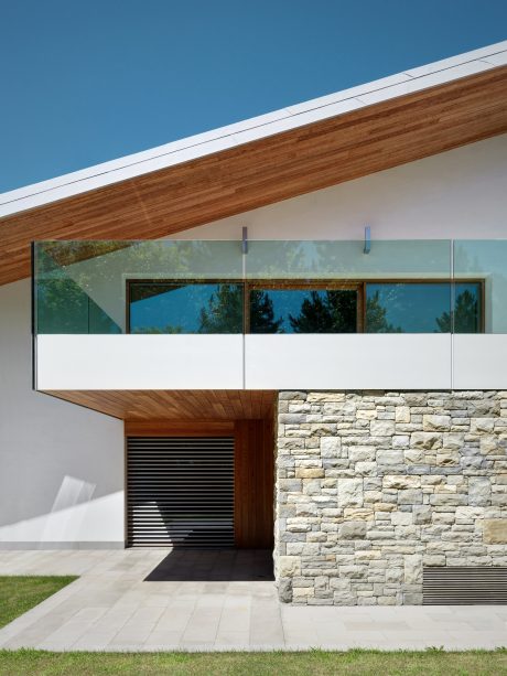 Modern architectural design featuring a wooden roof, large glass windows, and a stone facade.