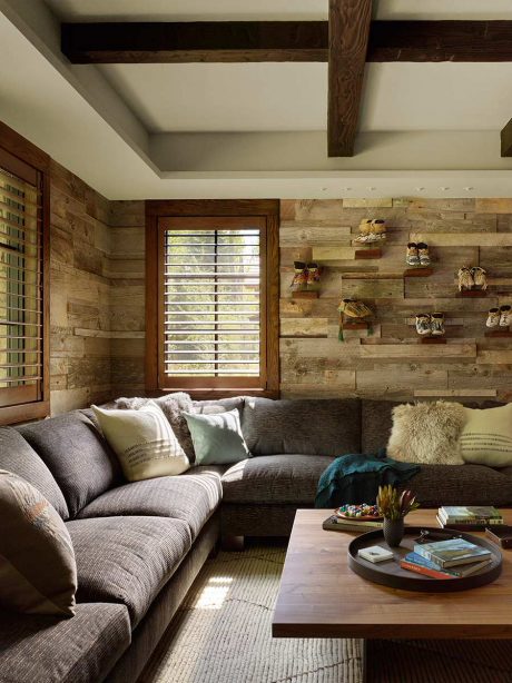 A cozy, rustic living room with exposed wooden beams, a comfortable sectional, and decorative shelving.