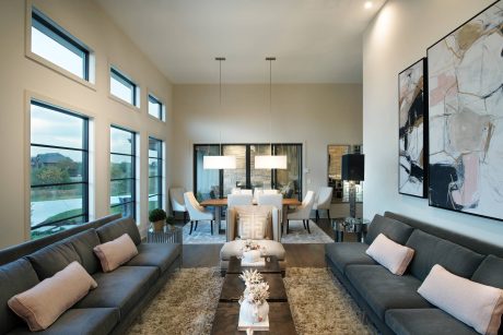 This open-concept living room features contemporary furniture, large windows, and an abstract art piece.