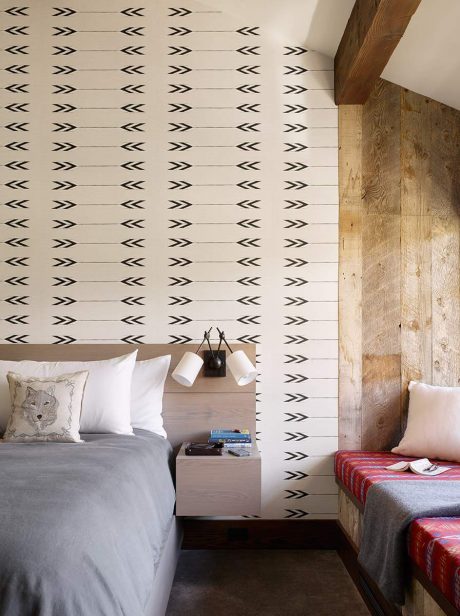 A modern bedroom with a patterned accent wall, wooden headboard, and contemporary furnishings.
