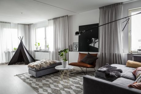 Cozy living room with modern furniture, textured rugs, and large windows allowing natural light.
