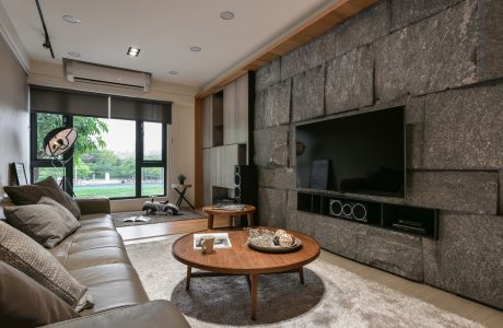 Modern living room with stone accent wall, wood furnishings, and sleek media console.