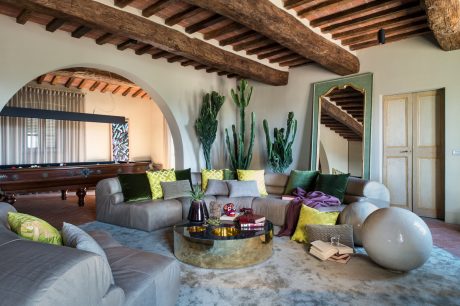 Cozy Mediterranean-style living room with rustic wooden beams, arched doorway, and potted cacti.