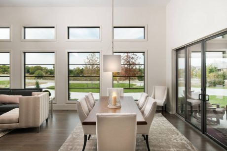 Spacious dining area with large windows showcasing scenic outdoor views. Modern, minimalist aesthetic.