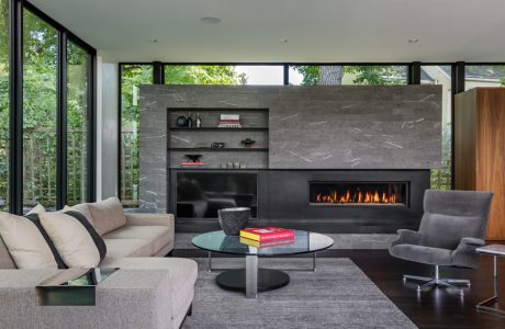 Sleek, contemporary living room with a striking slate fireplace, built-in shelving, and ample natural light.