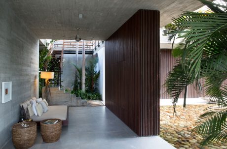An indoor tropical courtyard with concrete walls, wood paneling, and stone flooring.
