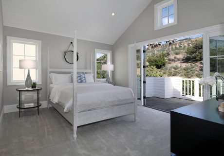Spacious, modern bedroom with high ceilings, large windows, and contemporary furnishings.
