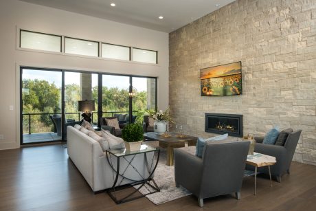Spacious living room with large windows, stone accent wall, fireplace, and modern furnishings.