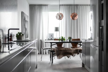Contemporary dining room with sleek black furniture, metallic pendant lights, and fur rug.