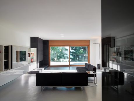 A modern living room with sleek built-in shelving, large windows, and dark sofas.