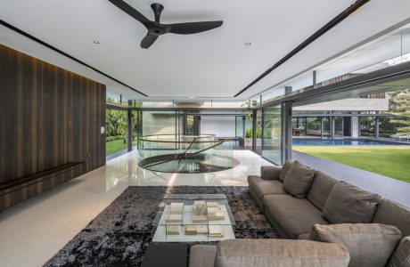 Sleek modern living room with glass walls, suspended ceiling, and circular glass centerpiece.