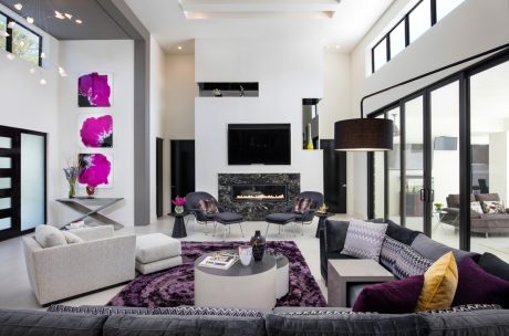 Spacious, modern living room with high ceilings, fireplace, and vibrant purple accents.