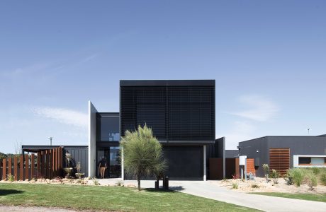 Sleek, modern architecture with black paneling, wooden accents, and sculptural landscaping.