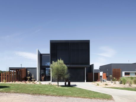 Sleek, modern architecture with black paneling, wooden accents, and sculptural landscaping.