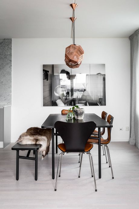 Modern dining area with black table, leather chairs, and a copper geometric light fixture.