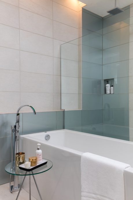 Minimalist bathroom with a freestanding bathtub, glass wall, and recessed shelving.