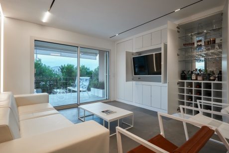 Modern living room with sleek cabinetry, glass wall, and minimalist furniture.