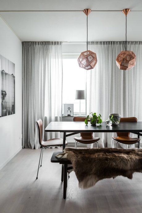 Modern dining room with minimalist decor, copper pendant lights, and a furry rug.