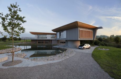 Contemporary architectural design with wooden accents, large windows, and a reflective pond.