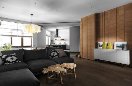 Spacious open-plan living area with wooden wall paneling, modern furnishings, and lighting.