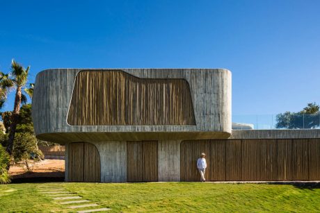 Striking concrete and wood structure with distinctive curved roofline and recessed entrance.