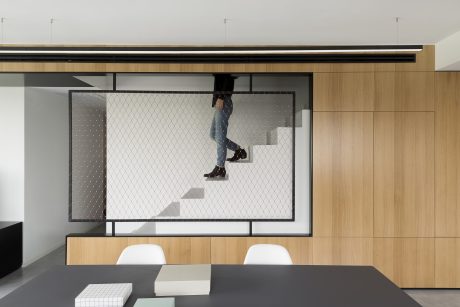 Minimalist interior design with wooden panels, metal frame, and a large framed artwork displaying a person climbing stairs.