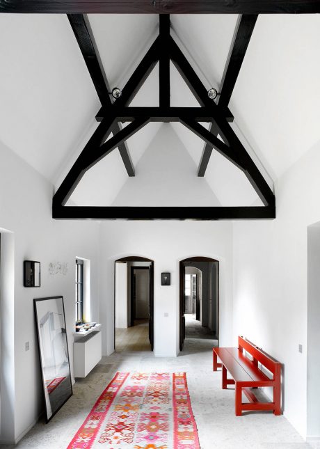 Striking black truss frame against white walls, contrasting with vibrant patterned rug.