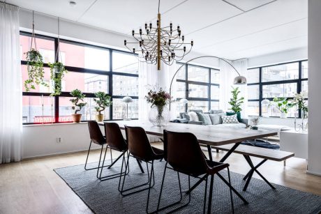 Spacious dining room with large windows, sleek furniture, and a statement chandelier.