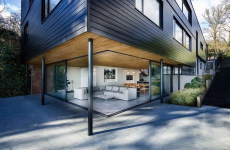 Modern wood-and-glass exterior with overhanging roof, open-concept living space.