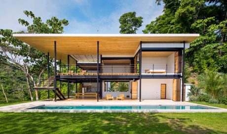 Modern tropical retreat with timber and steel frame, swimming pool, and lush greenery.