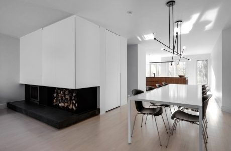 Minimalist open-concept living room with sleek white cabinetry, modern lighting, and a fireplace.