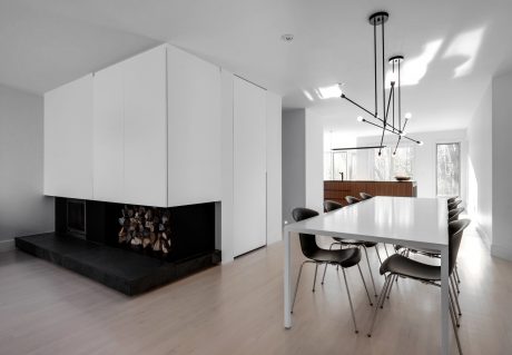 Minimalist open-concept living room with sleek white cabinetry, modern lighting, and a fireplace.