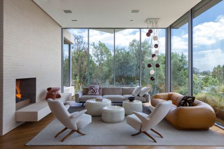 Elegant modern living room with floor-to-ceiling windows, fireplace, and sculptural lighting.
