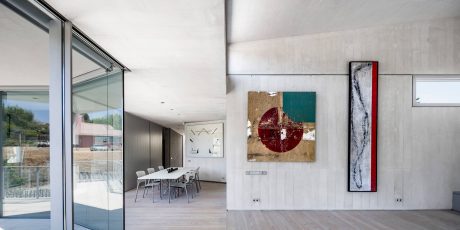 Spacious modern interior with glass walls, dining area, and abstract artworks on the walls.