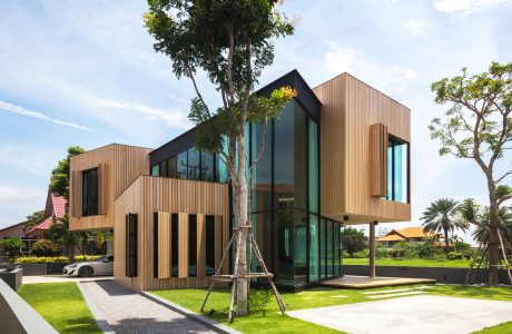A modern, sustainable building design featuring sleek wooden facades, expansive glass panels, and a lush surrounding landscape.