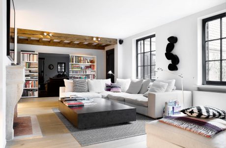 Spacious living room with modern furniture, wood-beamed ceiling, and built-in bookshelves.